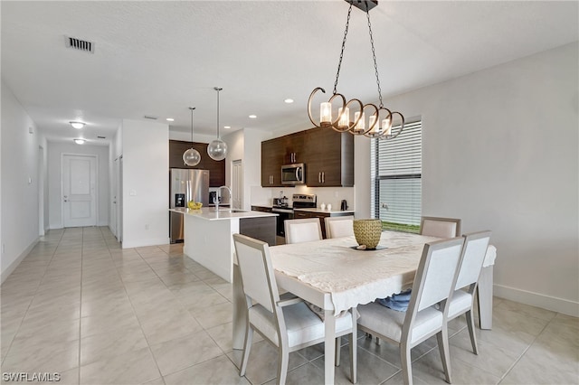 tiled dining space featuring a chandelier and sink