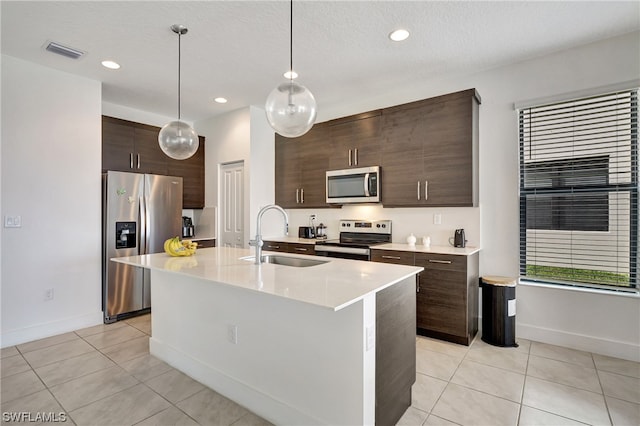 kitchen featuring a kitchen island with sink, pendant lighting, sink, dark brown cabinets, and stainless steel appliances