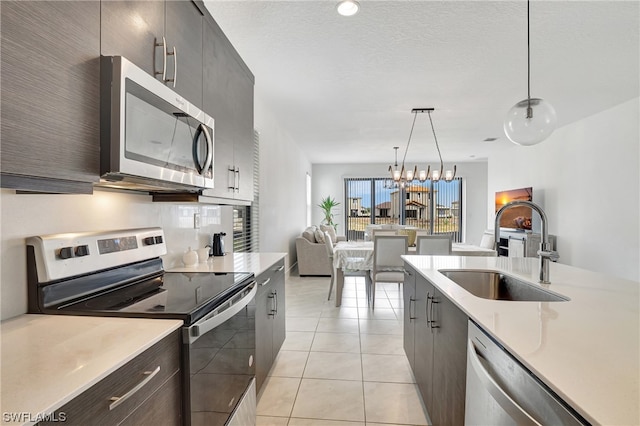 kitchen with a chandelier, stainless steel appliances, decorative light fixtures, light tile flooring, and sink