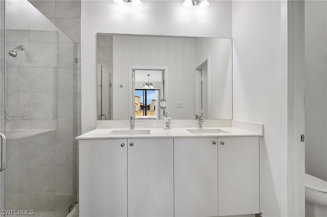 bathroom with toilet, dual bowl vanity, and an enclosed shower