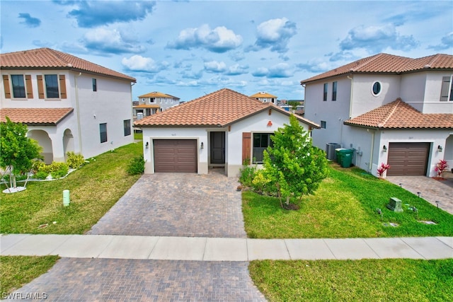 mediterranean / spanish-style home featuring a front lawn, central air condition unit, and a garage