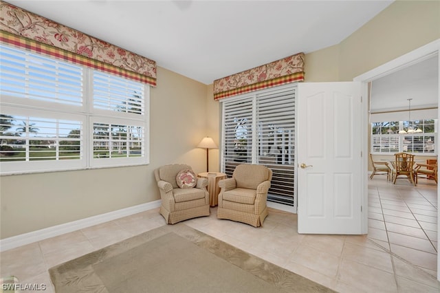 sitting room featuring light tile flooring, a healthy amount of sunlight, and a notable chandelier