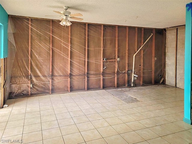 empty room featuring a textured ceiling, ceiling fan, and light tile flooring