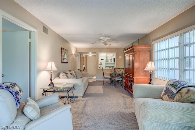 living room with carpet floors, ceiling fan, and a textured ceiling