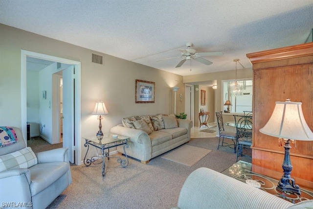 living room featuring light carpet, a textured ceiling, and ceiling fan with notable chandelier