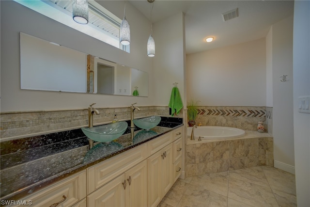 bathroom featuring a relaxing tiled bath, vanity with extensive cabinet space, and tile floors