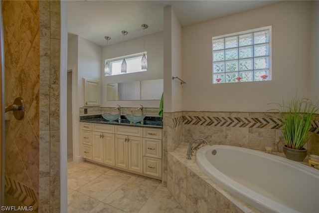 bathroom featuring tiled bath, vanity with extensive cabinet space, and tile floors