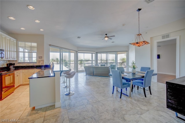 kitchen featuring backsplash, stove, ceiling fan, and a wealth of natural light