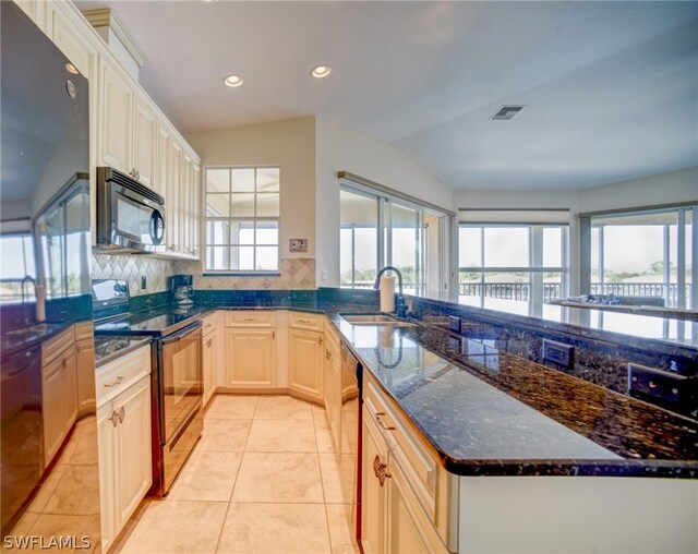 kitchen featuring sink, dark stone counters, appliances with stainless steel finishes, backsplash, and light tile flooring