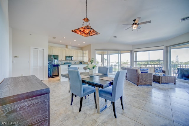 tiled dining room with a healthy amount of sunlight, ceiling fan, and lofted ceiling