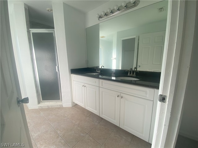 bathroom featuring tile flooring, double vanity, and a shower with shower door