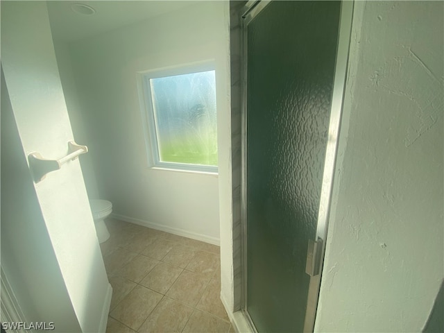 bathroom with walk in shower, tile flooring, and toilet