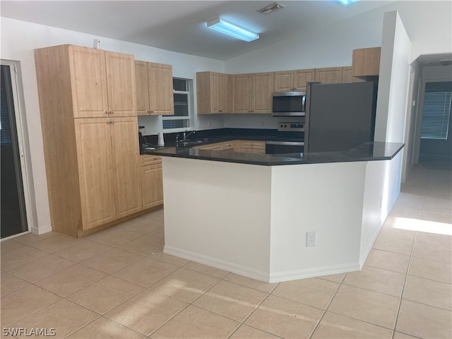 kitchen with light tile flooring, vaulted ceiling, appliances with stainless steel finishes, and sink