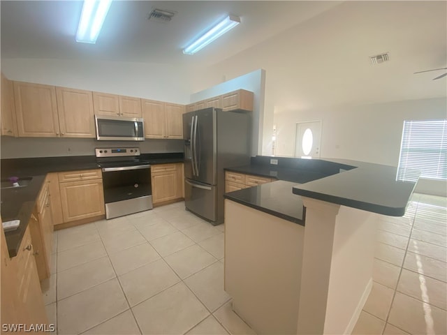 kitchen featuring light tile flooring, light brown cabinetry, stainless steel appliances, and kitchen peninsula