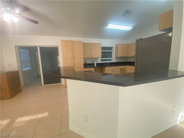 kitchen featuring light tile flooring, black fridge, ceiling fan, lofted ceiling, and sink