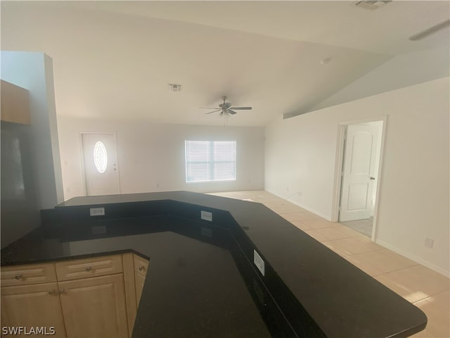 kitchen with lofted ceiling, light tile floors, light brown cabinets, and ceiling fan