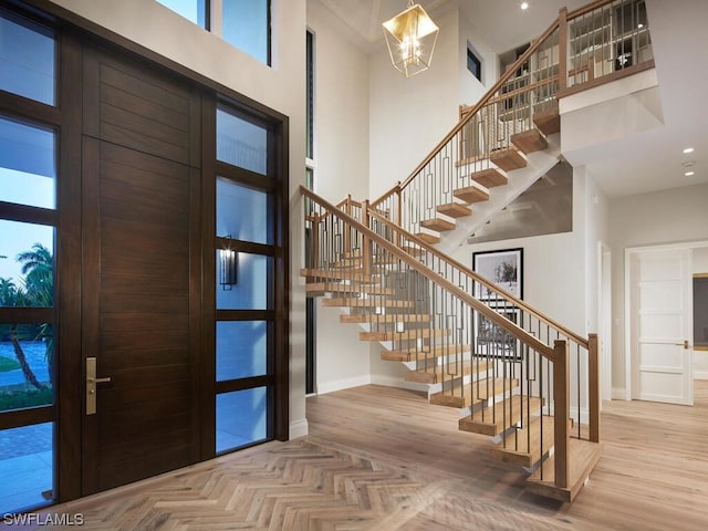 entryway with a high ceiling, parquet flooring, and a notable chandelier