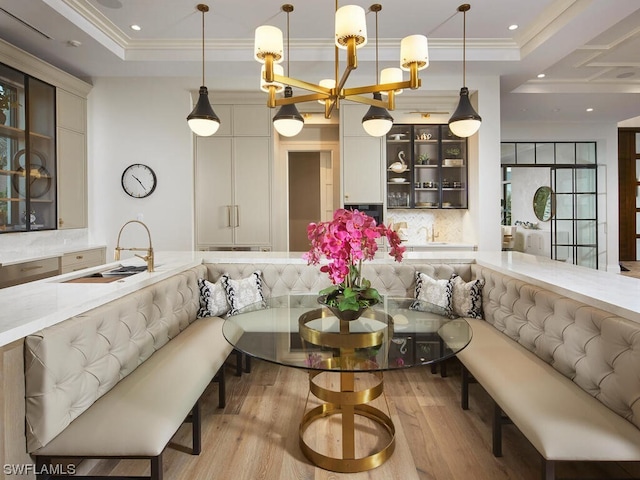 interior space featuring crown molding, a tray ceiling, light hardwood / wood-style floors, and breakfast area