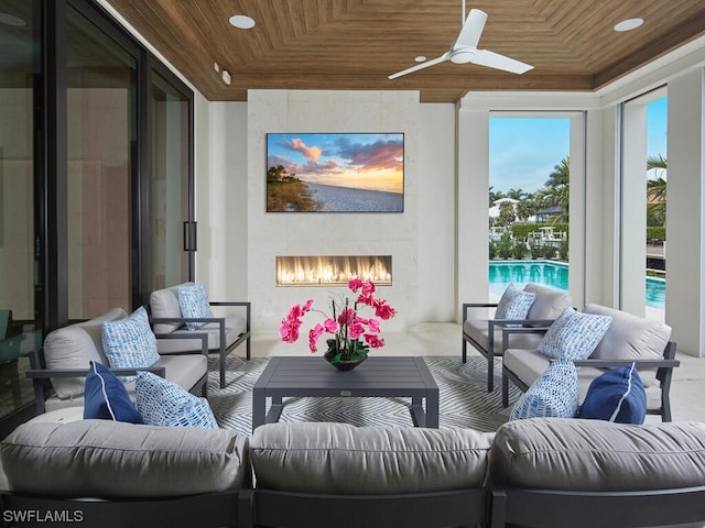 sunroom with ceiling fan, a large fireplace, and wood ceiling