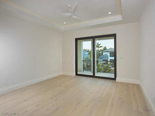 unfurnished room with ornamental molding, a raised ceiling, ceiling fan, and light wood-type flooring