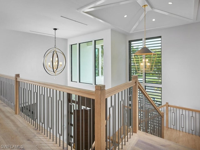 hallway featuring hardwood / wood-style flooring, vaulted ceiling, and a chandelier