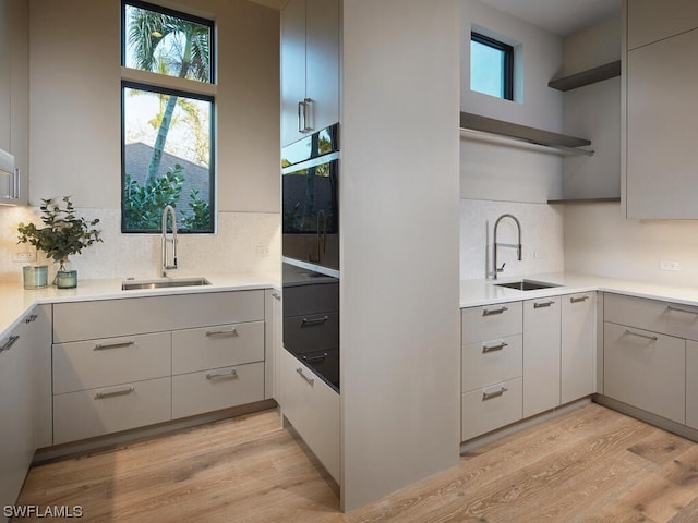 kitchen featuring sink, light hardwood / wood-style flooring, oven, and decorative backsplash