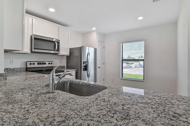 kitchen featuring appliances with stainless steel finishes, sink, white cabinets, and light stone counters