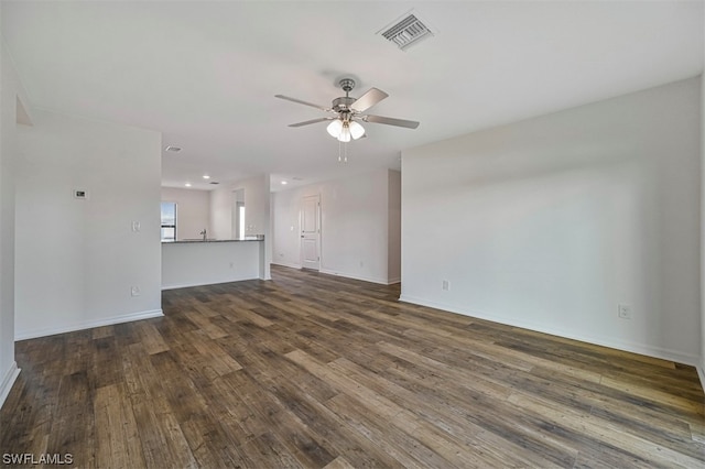 unfurnished living room featuring dark wood-type flooring and ceiling fan