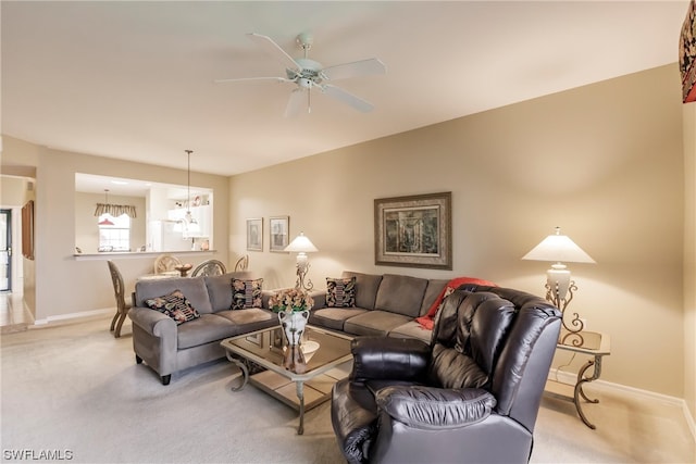 carpeted living room featuring ceiling fan with notable chandelier