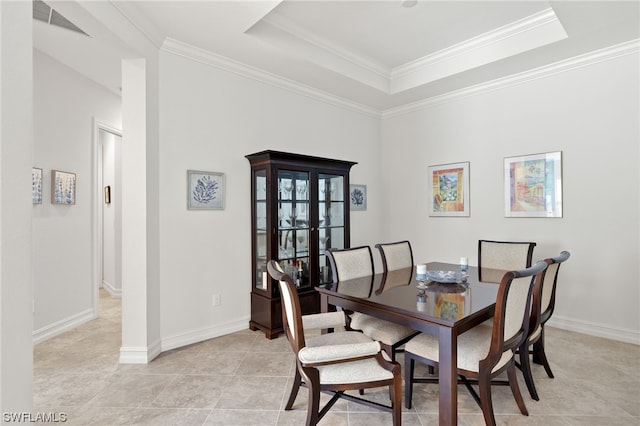 dining room featuring crown molding, a tray ceiling, and light tile patterned flooring