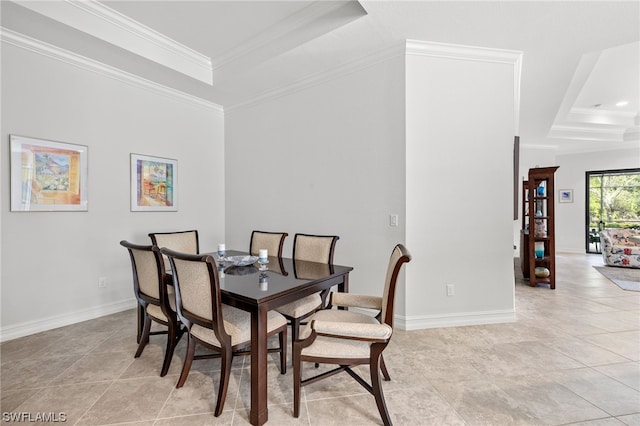 tiled dining room with a raised ceiling and ornamental molding