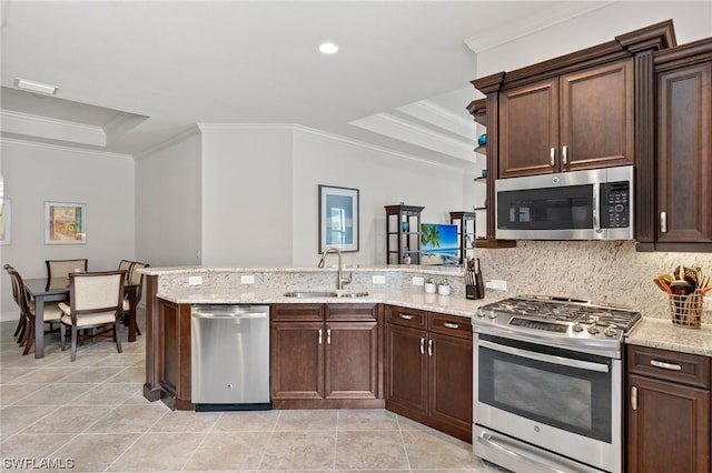 kitchen featuring sink, a raised ceiling, kitchen peninsula, and appliances with stainless steel finishes