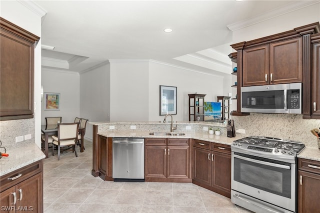 kitchen featuring sink, appliances with stainless steel finishes, a tray ceiling, ornamental molding, and kitchen peninsula