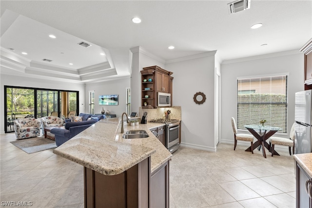 kitchen with light stone counters, sink, a healthy amount of sunlight, and appliances with stainless steel finishes