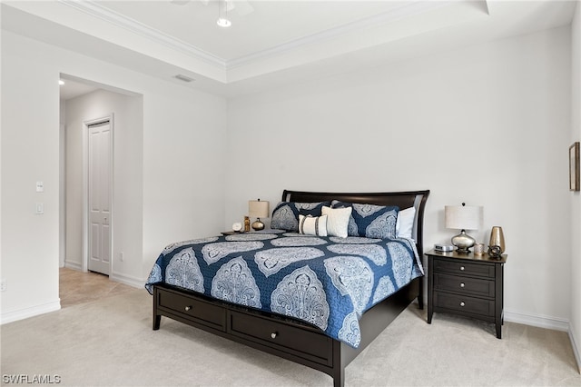 bedroom with crown molding, a tray ceiling, and light carpet