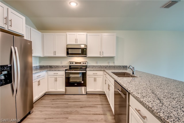 kitchen with light stone countertops, light hardwood / wood-style flooring, appliances with stainless steel finishes, white cabinetry, and sink