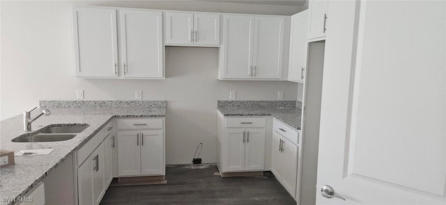 kitchen featuring white cabinets, light stone countertops, and a sink