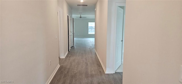 corridor featuring visible vents, baseboards, and wood finished floors