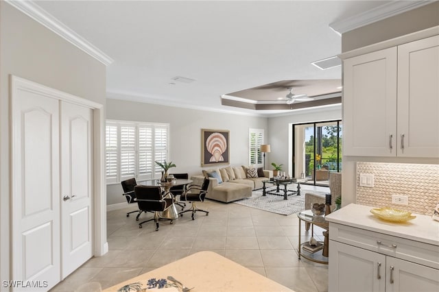 kitchen featuring a tray ceiling, ceiling fan, crown molding, and light tile patterned flooring