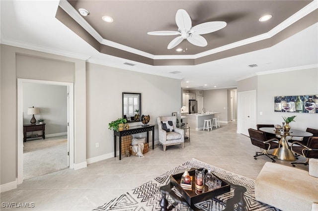 tiled living room featuring a tray ceiling, ornamental molding, and ceiling fan