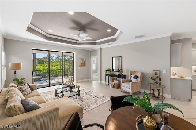 tiled living room featuring ceiling fan, a raised ceiling, and ornamental molding