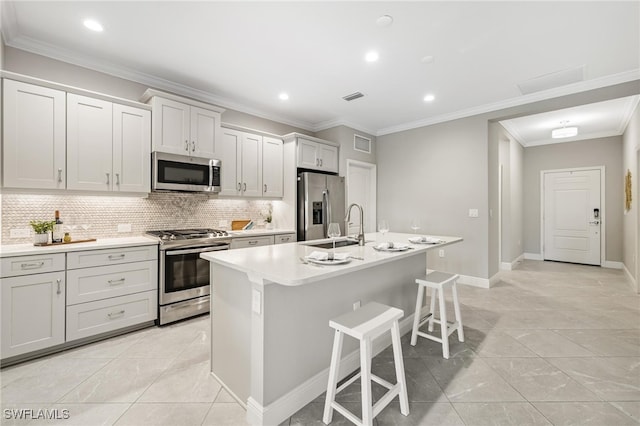 kitchen featuring backsplash, stainless steel appliances, an island with sink, and crown molding