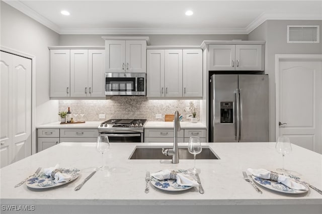 kitchen featuring crown molding, appliances with stainless steel finishes, light stone countertops, sink, and tasteful backsplash