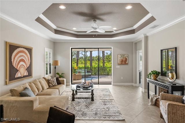 living room featuring ornamental molding, light tile patterned floors, a tray ceiling, and ceiling fan