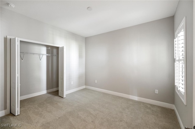 unfurnished bedroom with multiple windows, a closet, and light carpet