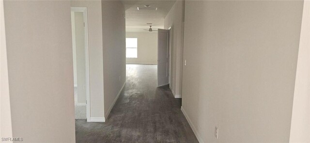 hallway featuring baseboards and dark wood-type flooring