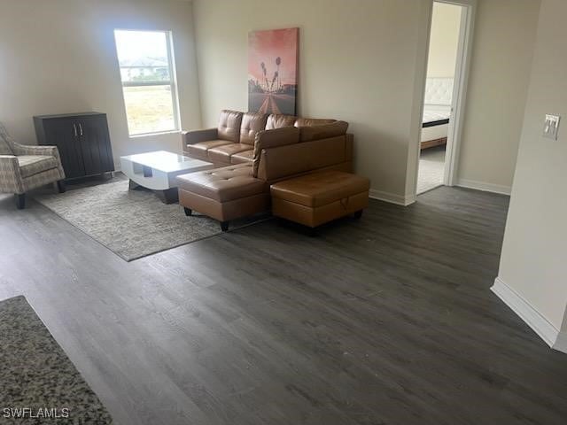 living area with baseboards and dark wood finished floors