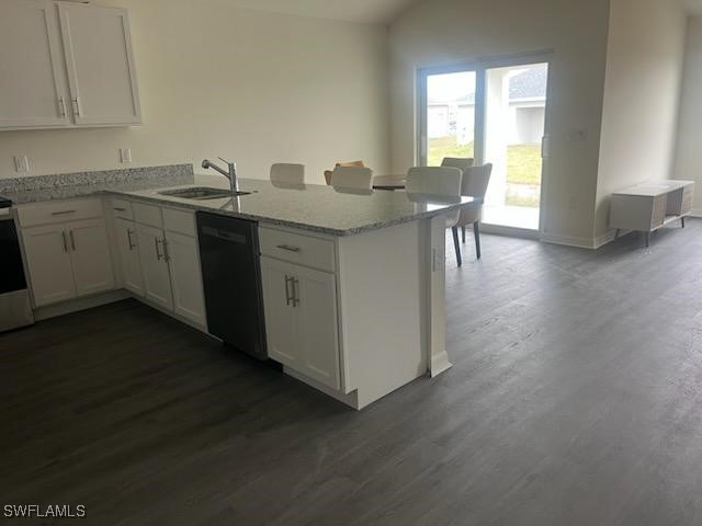 kitchen with a sink, a peninsula, white cabinets, light stone countertops, and dishwasher