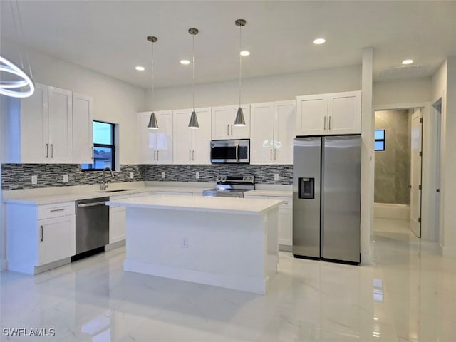 kitchen featuring sink, a center island, hanging light fixtures, white cabinets, and appliances with stainless steel finishes