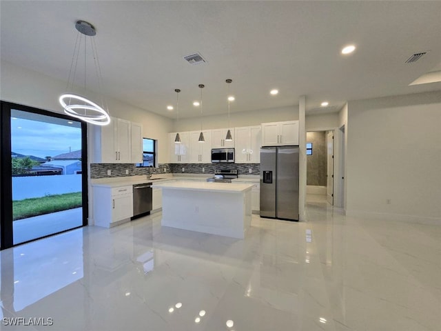 kitchen with pendant lighting, a center island, decorative backsplash, white cabinetry, and stainless steel appliances